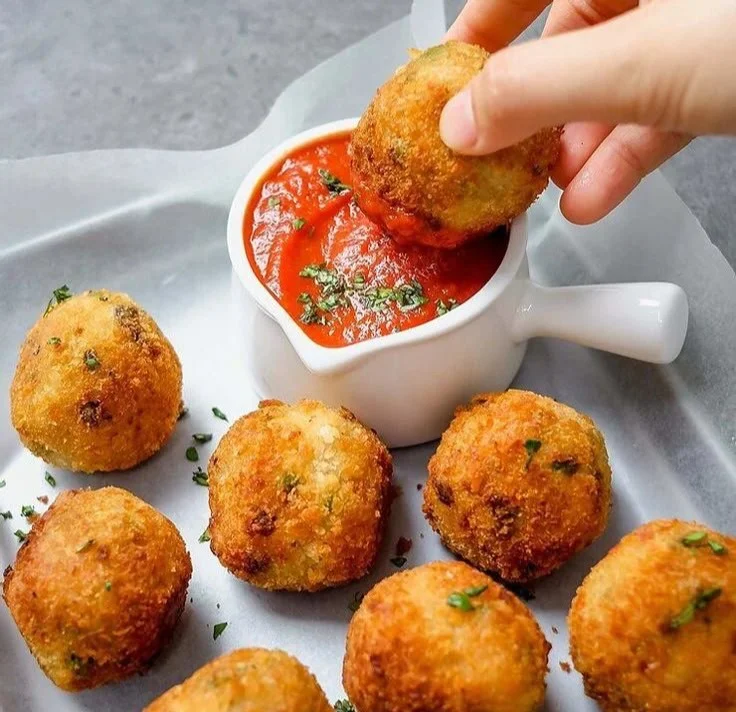 Cremige Pilz- und Erbsen-Arancini auf einem Teller serviert
