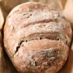 Ein Laib glutenfreies veganes Brot auf einem Holzbrett