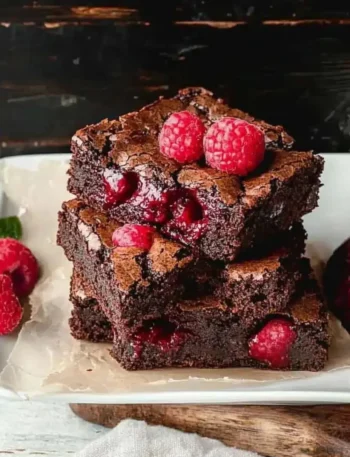 Himbeer-Brownies in einer Schüssel, mit frischen Himbeeren und Schokolade garniert.