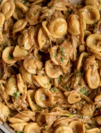 Karamellisierte Zwiebel-Pasta in einer Schüssel mit frischen Kräutern garniert.