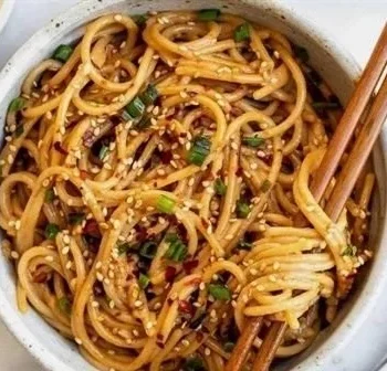 Schüssel mit Knoblauch-Sesamnudeln, garniert mit sesam, frisch und appetitlich.