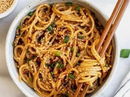 Schüssel mit Knoblauch-Sesamnudeln, garniert mit sesam, frisch und appetitlich.