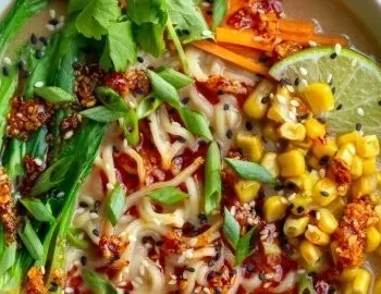 Schale mit Peanut Butter Miso Ramen, garniert mit frischem Gemüse und Kräutern.