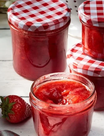 Selbstgemachte Erdbeermarmelade in einem Glas auf einem Tisch.