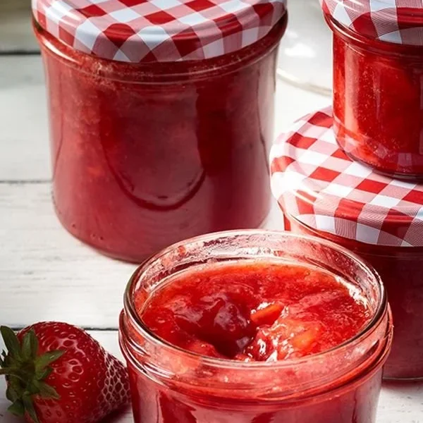 Selbstgemachte Erdbeermarmelade in einem Glas auf einem Tisch.