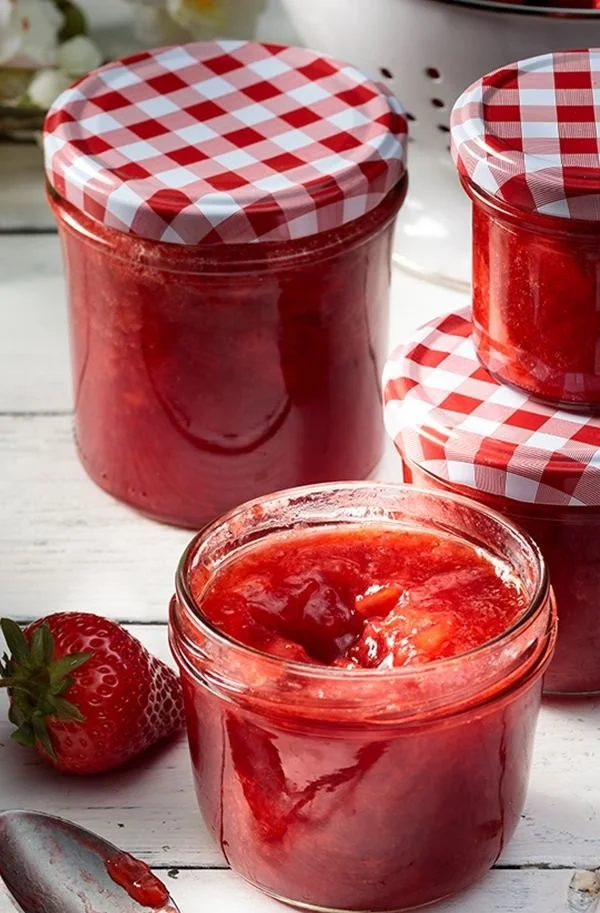 Selbstgemachte Erdbeermarmelade in einem Glas auf einem Tisch.