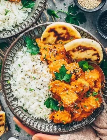 Tofu Tikka Masala serviert mit Reis und frischen Kräutern