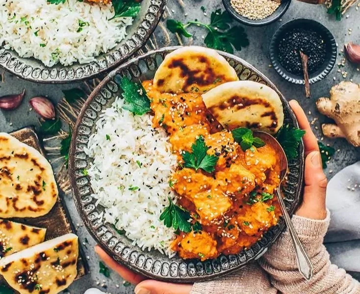 Tofu Tikka Masala serviert mit Reis und frischen Kräutern