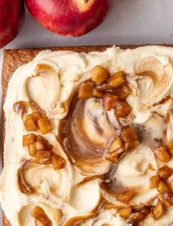 Veganer Apfelmus-Kuchen auf einem weißen Teller, garniert mit frischen Äpfeln.