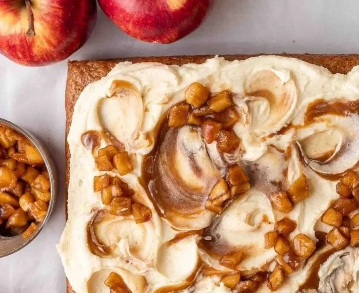 Veganer Apfelmus-Kuchen auf einem weißen Teller, garniert mit frischen Äpfeln.