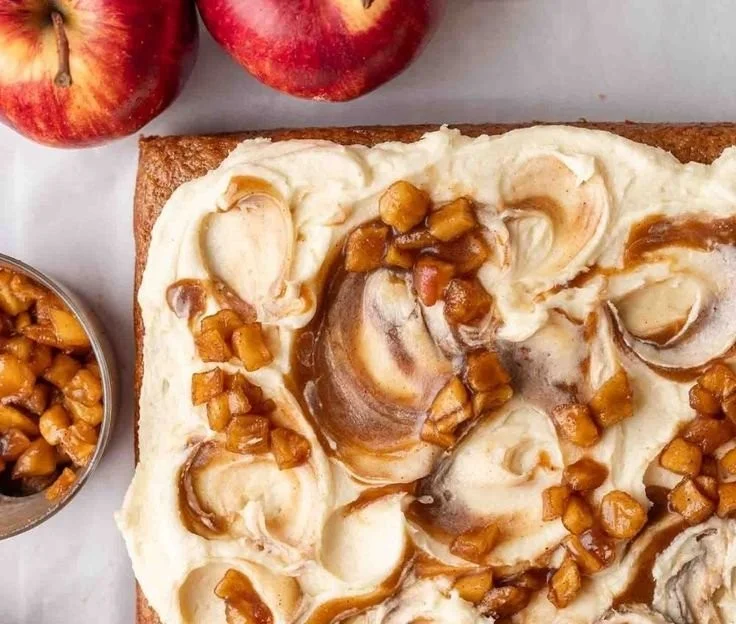 Veganer Apfelmus-Kuchen auf einem weißen Teller, garniert mit frischen Äpfeln.