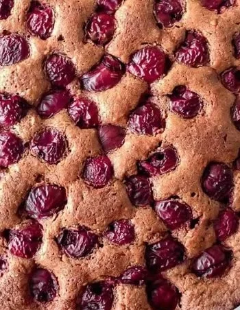 Veganer Schokoladen-Kirschkuchen auf einem Tisch dekoriert mit Kirschen