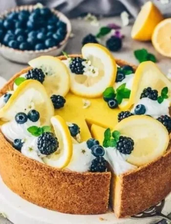 Veganes Zitronen-Cheesecake auf einem Teller mit frischen Zitronenscheiben