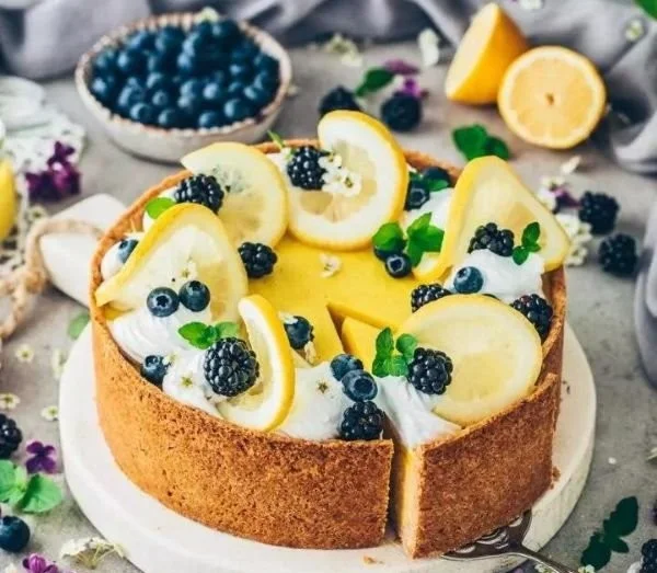 Veganes Zitronen-Cheesecake auf einem Teller mit frischen Zitronenscheiben