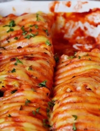 Vegane Lasagne Rollen auf einem Teller, serviert mit frischen Kräutern.