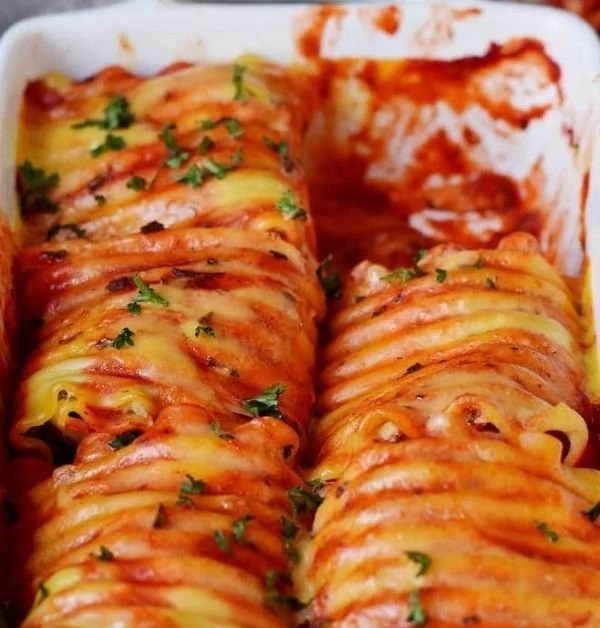 Vegane Lasagne Rollen auf einem Teller, serviert mit frischen Kräutern.