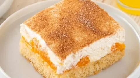 Veganer Fantakuchen mit Mandarinen und veganem Schmand serviert auf einem Teller.