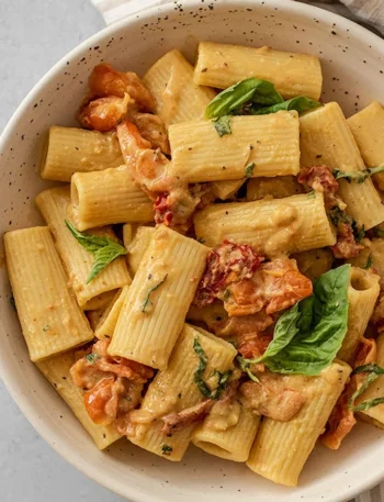 Ein Teller mit gebackener Hummus Pasta, garniert mit frischen Kräutern.