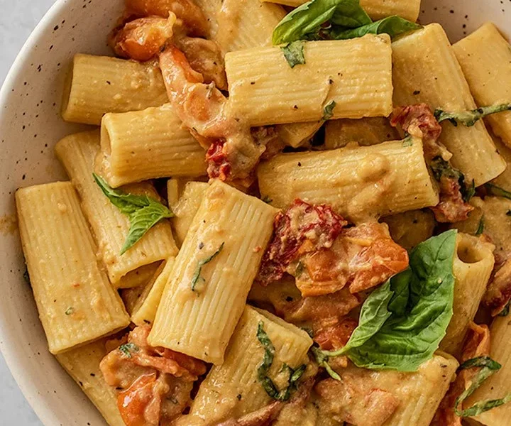 Ein Teller mit gebackener Hummus Pasta, garniert mit frischen Kräutern.