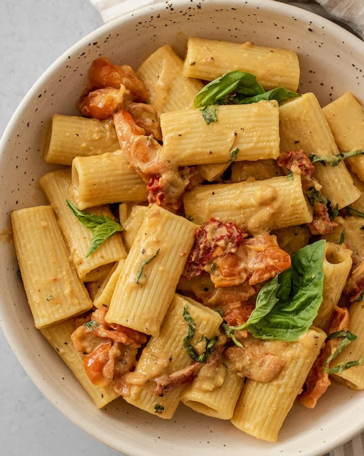 Ein Teller mit gebackener Hummus Pasta, garniert mit frischen Kräutern.