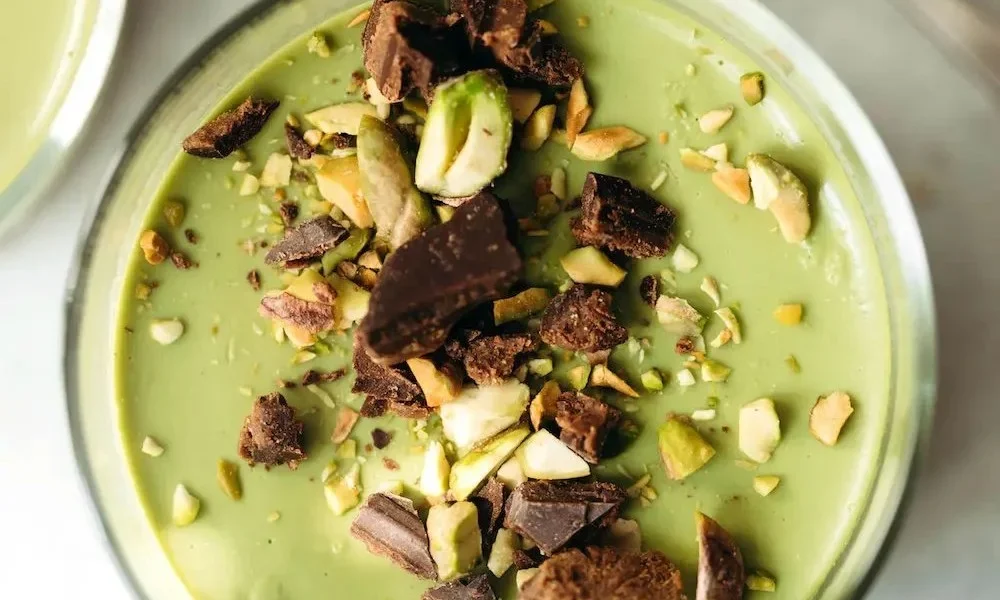 Chocolate Hazelnut Matcha Pudding in einer Schüssel mit Nüssen und Matcha-Pulver dekoriert.