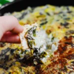 Cremiger veganer Spinats- und Artischockendip in einer Schüssel serviert.