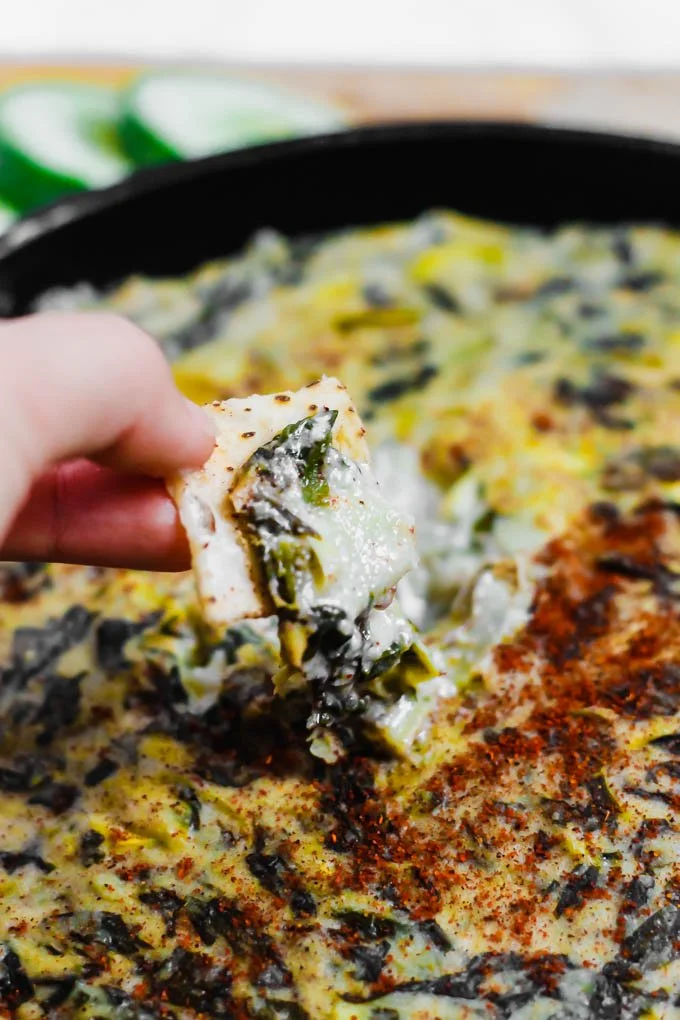 Cremiger veganer Spinats- und Artischockendip in einer Schüssel serviert.