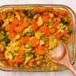 Veganer Gemüse-Reisauflauf auf einem Teller serviert, garniert mit frischen Kräutern.