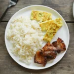 Schüssel mit Knoblauchbratreis (Filipino Sinangag) auf einem Holztisch