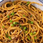 Vegane Knoblauchnudeln auf einem Teller serviert mit frischem Basilikum.
