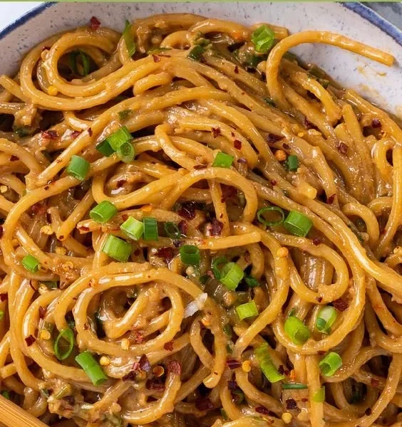 Vegane Knoblauchnudeln auf einem Teller serviert mit frischem Basilikum.