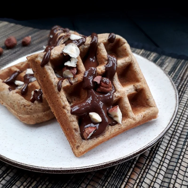 Vegane glutenfreie Haselnuss Waffeln auf einem Teller, angerichtet mit Schokolade