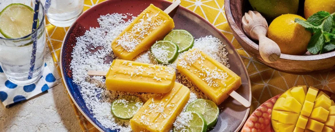 Selbstgemachtes Mango-Limetten-Eis am Stiel in einer bunten Eistruhe