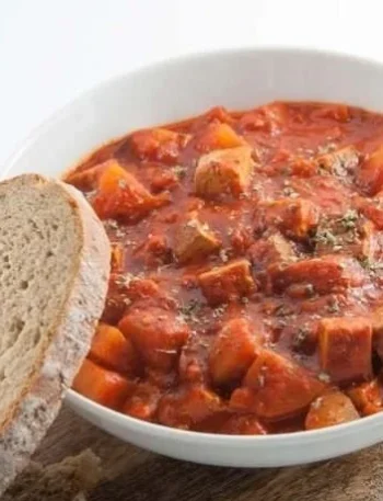 Veganes Gulasch mit Räuchertofu und Kartoffeln auf einem Teller angerichtet.