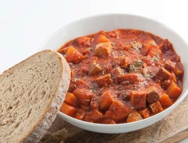 Veganes Gulasch mit Räuchertofu und Kartoffeln auf einem Teller angerichtet.