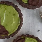 Veganer Matcha Tart in einer modernen Präsentation, dekoriert mit frischen Zutaten.