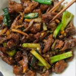 Vegan Mongolian Rindfleisch mit Pilzen auf einem Teller serviert.