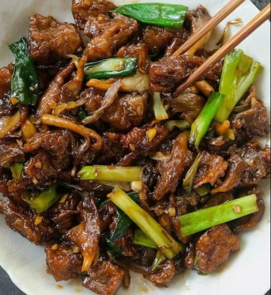 Vegan Mongolian Rindfleisch mit Pilzen auf einem Teller serviert.