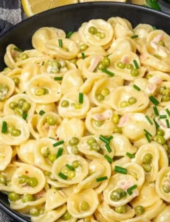 Vegane cremige Zitronenpasta mit Erbsen in einer Schüssel serviert.