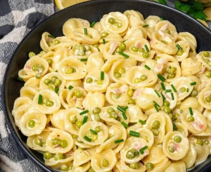 Vegane cremige Zitronenpasta mit Erbsen in einer Schüssel serviert.