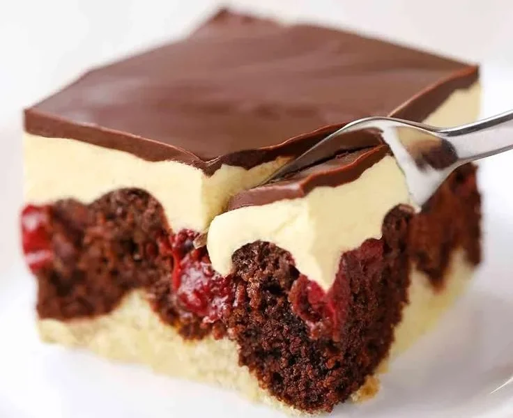 Vegane Donauwelle auf einem Teller mit frischen Beeren und Schokoladenglasur