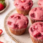 Vegane Erdbeermuffins mit frischen Erdbeeren auf einem Kuchenteller