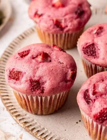 Vegane Erdbeermuffins mit frischen Erdbeeren auf einem Kuchenteller