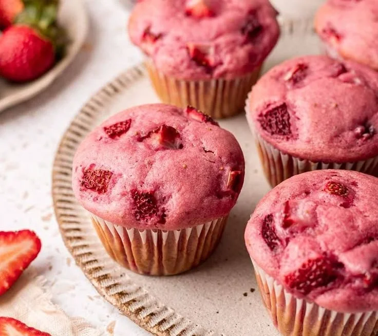 Vegane Erdbeermuffins mit frischen Erdbeeren auf einem Kuchenteller