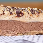 Vegane Snickers Torte mit Erdnüssen und Schokolade auf einem Teller serviert