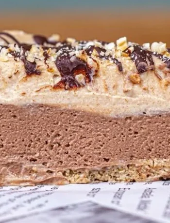 Vegane Snickers Torte mit Erdnüssen und Schokolade auf einem Teller serviert