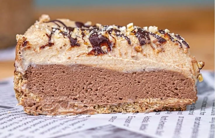 Vegane Snickers Torte mit Erdnüssen und Schokolade auf einem Teller serviert