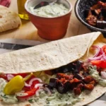 Veganer Auberginen Kebab mit Tzatziki auf einem Teller serviert