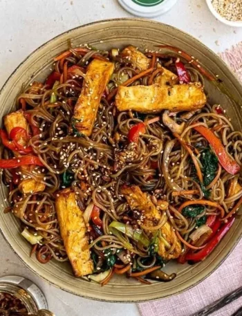Veganes Japchae mit buntem Gemüse und Glasnudeln, serviert in einer Schüssel.
