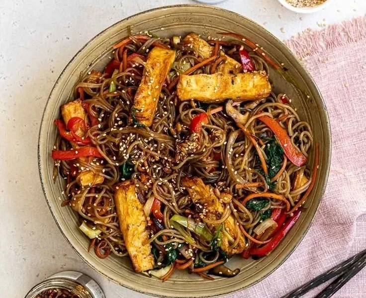 Veganes Japchae mit buntem Gemüse und Glasnudeln, serviert in einer Schüssel.